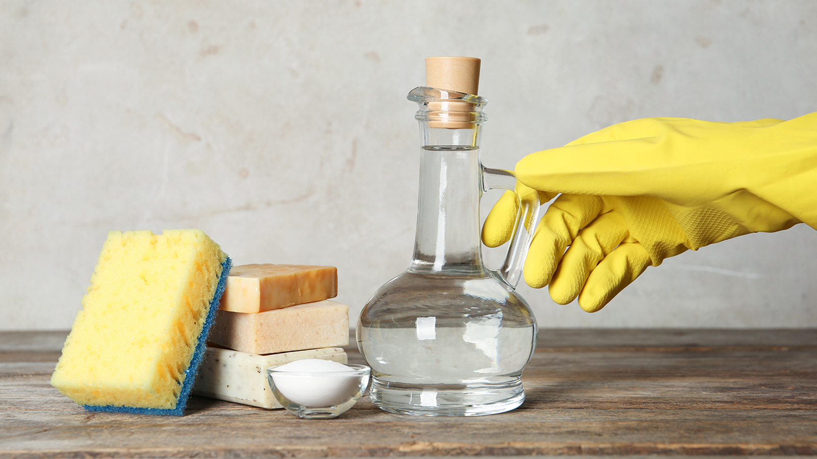 mano con guanto giallo che prende contenitore in vetro con liquido dentro